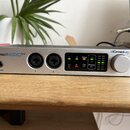 Stříbrný audio rozhraní s nápisem ConnectAUDIO 2/4 a logem iConnectivity. Přední panel obsahuje dva kombinované XLR/jack vstupy označené čísly 1 a 2,…