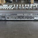 Zadní strana stříbrného kontroléru s nápisy X-TOUCH a CONCEIVED AND DESIGNED BY BEHRINGER GERMANY. Jsou zde vidět konektory pro AC IN, POWER (spínač…
