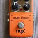 Oranžový efekt pedál s nápisy Delay, TIME CORE a logem nux. Horní ovládací panel obsahuje tři černé otočné knoflíky s popisky Time, Mix a Repeat, pře…