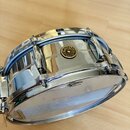 Stříbrný kovový malý buben s chromovaným povrchem. Na korpusu je umístěno kulaté logo s nápisem Gretsch, ORIGINAL SINCE 1881. Na horním obruči je vid…