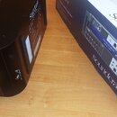 Černý rackový přístroj s logem Soundcraft na horní straně a varovným symbolem trojúhelníku s bleskem na zadní straně. Vedle přístroje je položen modr…