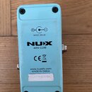 Zadní strana modrého efekt pedálu z kovu. Na spodní části je uveden nápis NUX MINI CORE, značka CE, symbol přeškrtnuté popelnice a web www.nuxefx.com…