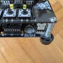 Detailní pohled na elektronický modul s černým plošným spojem. Na spodní části desky je bílý nápis „Shruthi-1 Mutable Instruments Dual SVF board v0.2…
