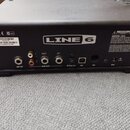Zadní strana černého elektronického zařízení s logem LINE 6. Jsou zde viditelné konektory s popisky AMP OUT, MAIN OUTS (L RIGHT, R), OPTICAL OUT, USB…