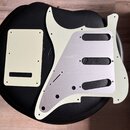 Sada plastových a kovových dílů pro elektrokitaru v krémové barvě. Soubor obsahuje pickguard s přiloženým hliníkovým stíněním a krytku elektroniky. N…