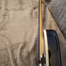 Detailní pohled na krk a hranu korpusu elektrické kytary. Nástroj má světlý dřevěný krk, hnedý hmatník a černý lakovaný korpus s bílým lemováním. Na…