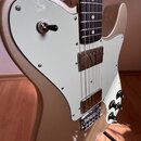 Elektrická kytara s kovovým, zlatavým povrchem a bílým pickguardem. Nástroj má dva snímače s kovovými kryty, jeden přepínač a tři oválné ovládací kno…
