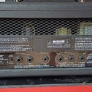 Zadní strana kytarového komba v černém vinylovém potahu s kovovými rohy a mřížkou. Na zadním panelu je nápis Blackstar, Designed and Engineered by Bl…