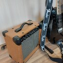 Kytarový kombozesilovač v hnědém textilním potahu s černými plastovými rohy a úchytem. Na předním panelu je nápis Fender, ovládací prvky a šedá texti…