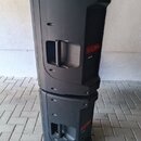 Dvě černé plastové aktivní reprodukce stohované na sebe na dlažbě. Na boku horního reproduktoru je červený štítek s nápisem t.box PA300P a pod ním me…