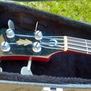 Černá hlava basové kytary s nápisem Epiphone v bílé barvě. Na povrchu je vidět logo ve tvaru stylizovaného listu a další nečitelný symbol. Nástroj je…