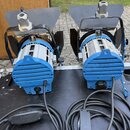 Dvě modré studiové lampy s hliníkovým chladičem a černými klapkami. Na zadní části každého přístroje je vidět bílý nápis ARRI. Lampy jsou připojeny k…