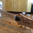 Elektrická kytara s přírodním dřevěným povrchem krku a hlavy. Na hlavě je černý nápis Paul Reed Smith® a na hmatníku jsou viditelné vložky ve tvaru p…