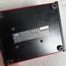 Fotografie zachycuje spodní stranu černého zařízení s červeným rámem. Na spodní části je bílý štítek s logem VOX a nápisy: Vox Amplification Ltd, MOD…