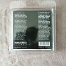Fotografie znázorňuje balení kytarových strun v průhledném plastovém obalu. Na černém pozadí je text v němčině a angličtině, značka THOMASTIK-INFELD…