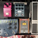 Na fotografii je pedálboard se čtyřmi efekty. Vlevo je stříbrný pedál s nápisem BOSS, v horní střední části šedý pedál značky tc electronic s nápisem…