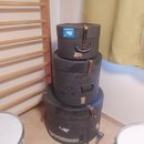 Tři černé kulaté přepravní kufry naskládané na sebe. Kufry jsou vyrobeny z tmavého materiálu s koženými úchytky a zapínacími pásy. Povrchy vykazují v…