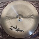 Kruhový činel z kovu v přirozené zlatavé barvě s viditelným kovánívým povrchem. V dolní části je černý nápis Zildjian. U středu se nachází bílá nálep…