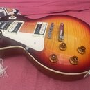 Elektrická kytara s trupem ve tvaru singlecut a barevným přechodem od žluté k tmavě červené (sunburst). Nástroj má dva humbuckery s bílými rámečky, b…