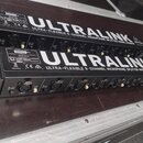Dvě černé rackové jednotky s nápisem ULTRALINK a textem ULTRA-FLEXIBLE 8-CHANNEL MICROPHONE SPLITTER MODEL MS8000. Na šasi je viditelné logo behringe…