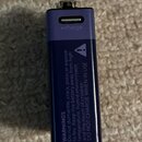Fialový obdélníkový modul s USB portem a kovovým kontaktem v horní části. Na horní straně je nápis "charge" s ikonou blesku. Boční strana obsahuje va…