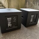Dva černé aktivní subwoofery s matným povrchem. Na zadním panelu obou přístrojů je bílý nápis ALTO PROFESSIONAL a modelové označení TS312S POWERED SU…