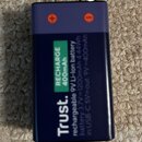 Tmavě modrá dobíjecí baterie s kapacitou 400 mAh. Na povrchu je bílý nápis Trust., zelený štítek RECHARGE 400mAh a text rechargeable 9V Li-ion batter…