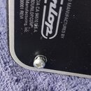 Detailní pohled na černý povrch zařízení s bílými nápisy. Je zde vidět logo Dunlop a texty MANUFACTURED BY, CIA CA 94510 U.S.A., DUNLOP.COM, Manufact…