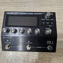 Černý kytarový procesor s nápisem BOSS GT-1000CORE GUITAR EFFECTS PROCESSOR. Zařízení má digitální displej, šest kovových otočných ovladačů s čísly 1…