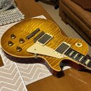 Elektrická kytara typu Les Paul s žlutým plamenovitým topem a tmavě červenými boky. Nástroj má dva humbuckery s krémovými rámečky, krémový pickguard…