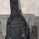 Černý poloměký pouzdro (gig bag) na kytaru s několika zipovými kapsami. V dolní části je přišita bílá štítek s logem "DreamCatcher". Povrch materiálu…