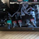 Fotografie zachycuje vnitřek černého elektronického zařízení s otevřeným šasi. Uvnitř jsou vidět dvě základní desky s osazenými součástkami, kabeláž…