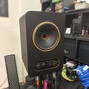 Černý studiový monitor umístěný na stojanu. Reproduktor má zlatý okraj a v dolní části je ovládací panel s nápisem GOLD 8 a logem ELNOY. Panel obsahu…