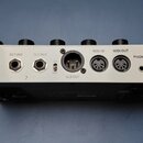 Zadní strana stříbrného hudebního zařízení s řadou konektorů. Jsou zde nápisy INPUT, SEND, RETURN, OUTPUT, LIFT GND, XLR OUT, MIDI IN, MIDI OUT, PHON…