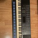 Černý digitální klavír s bílými a černými klávesami. V levém horním rohu je nápis YAMAHA a v levém dolním rohu nápis MUSIC-STATION. Nástroj obsahuje…