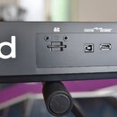 Detailní pohled na zadní panel černého hudebního nástroje. Jsou zde vidět konektory a nápisy: "SD HC", "COMPUTER" s ikonou USB a "FOR UPDATE". Panel…