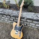 Světlé elektrické kytary typu Telecaster s černým pickguardem a javorovým hmatníkem. Na hlavě krku je viditelné logo Fender. Tělo má přirozenou dřevě…