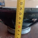 Fotografie zachycuje detail černého reproduktoru z boku. Přes komponentu je přiložena žlutá skladovací metr, která ukazuje rozměr v centimetrech. Pov…