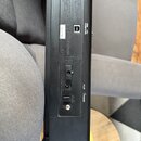 Fotografie zachycuje zadní panel černého elektronického zařízení. Jsou zde viditelné konektory s popisky USB COMPUTER, DC IN a POWER, dále vypínač a…