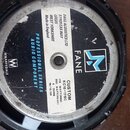 Fotografie zachycuje zadní stranu reproduktoru s černým kovovým rámem. Na středovém magnetu je bílý štítek s nápisy FANE ACOUSTICS LTD, SANDLEAS WAY,…