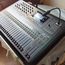 Digitální mixážní pult stříbrné barvy s velkým množstvím posuvníků, tlačítek a otočných ovladačů. Na pravé straně je vidět logo Soundcraft a název mo…