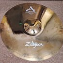 Kruhový mosazný činel s viditelným broušením povrchu. Na horní části je bílý nápis CUSTOM 20th Anniversary Ride MEDIUM THIN 21"/53 cm s doprovodným l…