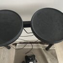 Dvě černé gumové pady elektronických bubnů s logem YAMAHA v horní části. Povrchy padů vykazují známky používání ve formě mírného opotřebení a zmatněn…