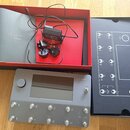 Šedý kytarový procesor s displejem a osmi stoupacími spínači označenými písmeny A až H. Na přístroji je v pravém horním rohu nápis QUAD CORTEX a u ov…