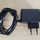 Černý síťový adaptér s přívodním kabelem a konektorem typu jack. Adaptér má hranatý tvar a zakončení pro zásuvku typu C. Kabel je svázaný černým such…
