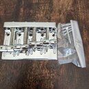 Stříbrný kovový kobylník na elektrickou kytaru s pěti sedly a odpružineným mechanismem. Na horní hraně je vyryt nápis GOTOH JAPAN. Vedle nástroje se…