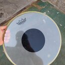 Průhledná bubenová kožíška s černým kruhem uprostřed a bílým okrajem. V horní části je černé logo REMO s korunkou a nápisem CONTROLLED SOUND® USA. Po…