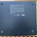 Fotografie zachycuje spodní stranu černého elektronického hudebního nástroje. Na černé ploše je umístěn velký textový blok s varovnými doporučeními v…