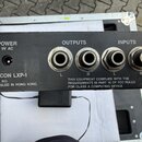 Zadní strana černého elektronického zařízení s nápisy LEXICON LXP-1, SERIAL NO. a ASSEMBLED IN HONG KONG. Jsou zde čtyři konektory, rozdělené do skup…