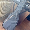 Černý poloměký pouzdro (gig bag) na kytaru s hnědým prošíváním lemů. Na horní části je bílý nápis RITTER a v dolní části u zipu malé logo s nápisem R…